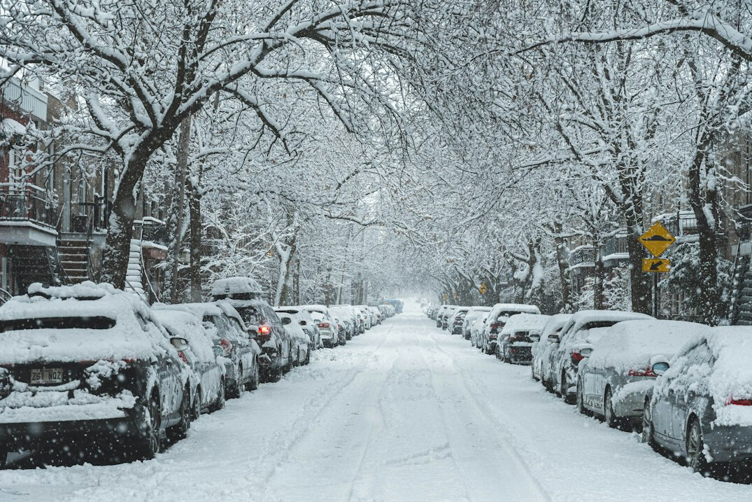 A quiet residential Montreal street covered in snow with parked cars