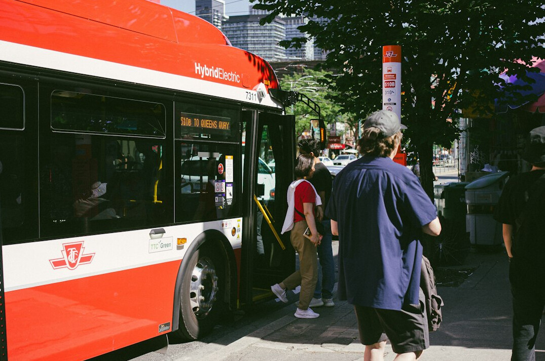 Pedestrians crossing a busy downtown Toronto street in front of a city bus