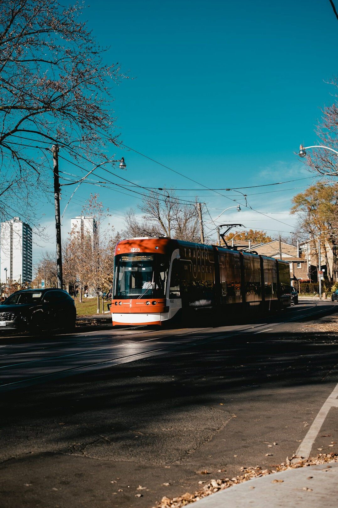 A yellow streetcar moving along a Toronto neighborhood street