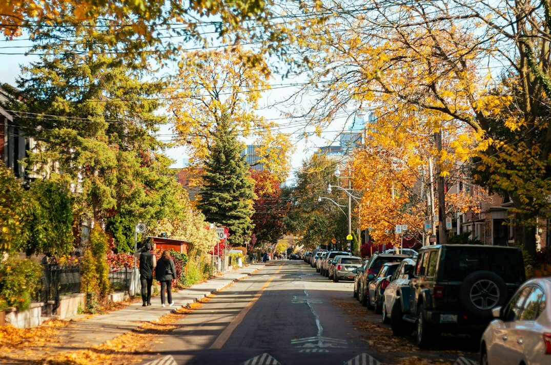 Two people walking together down a Toronto neighborhood sidewalk